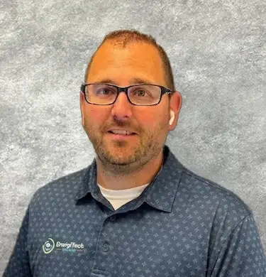 revor Magnuson, Service Manager at EnergiTech Services, wearing a blue EnergiTech polo shirt and glasses against a neutral studio backdrop.